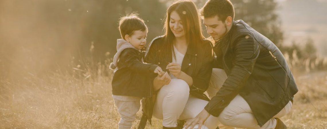 A cheerful family bonding outdoors with a soccer ball, enjoying a sunny day in the grass.