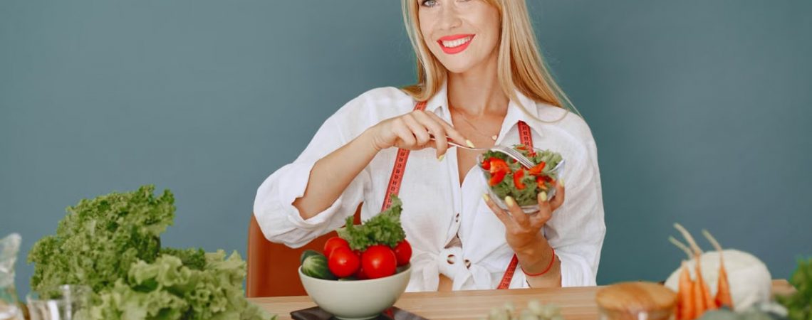 Blonde woman enjoying a fresh salad surrounded by vegetables, promoting healthy eating.